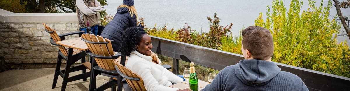 Guests seated on a lakeside patio enjoying drinks and views of Deer Creek Lake.