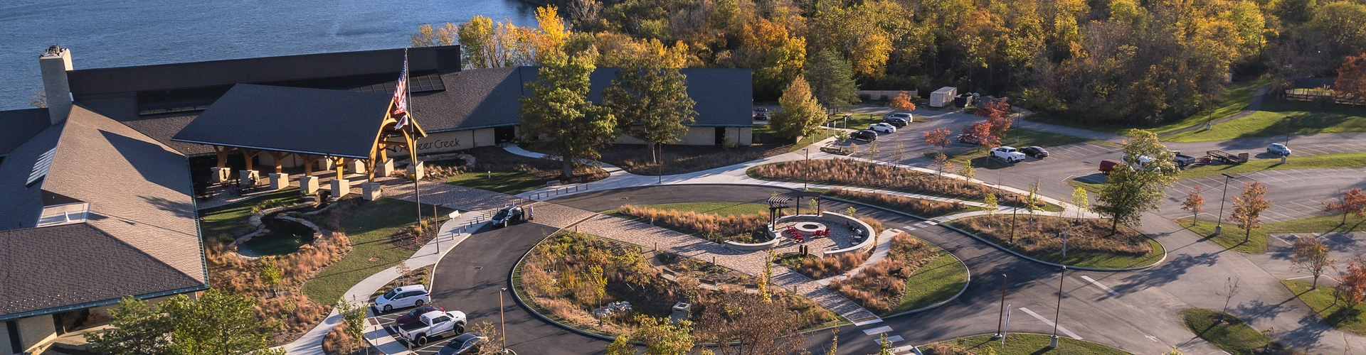 An aerial view of the main property at deer creek with winding pathways, densely populated trees, and the lake in the background