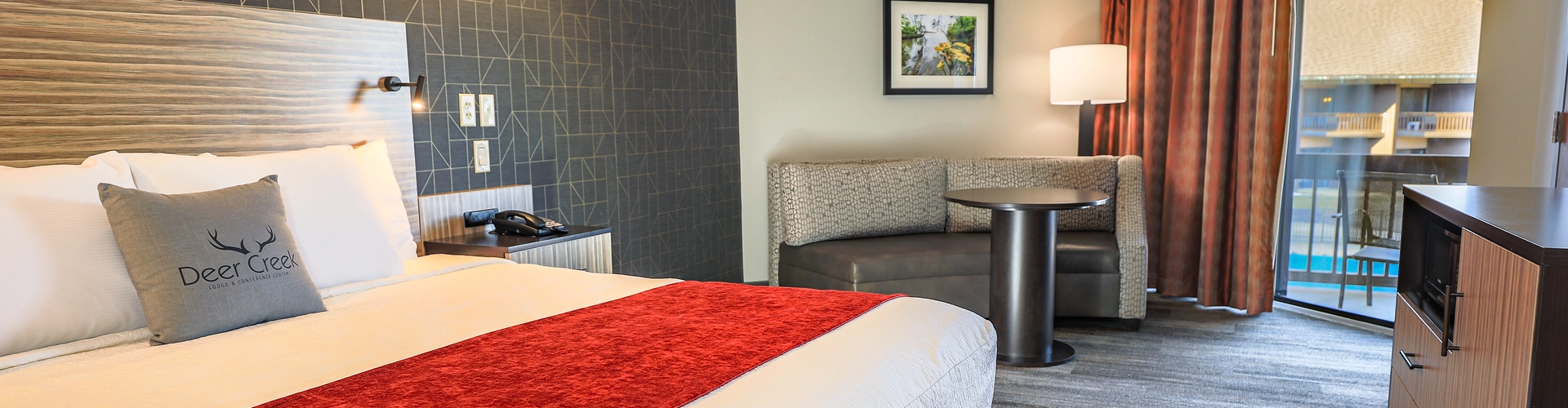 King Bed with corner sofa and table nearby a sliding door.